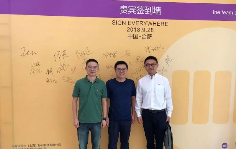三名男子在写有2018.9.28中国岳阳的签到墙前合影
