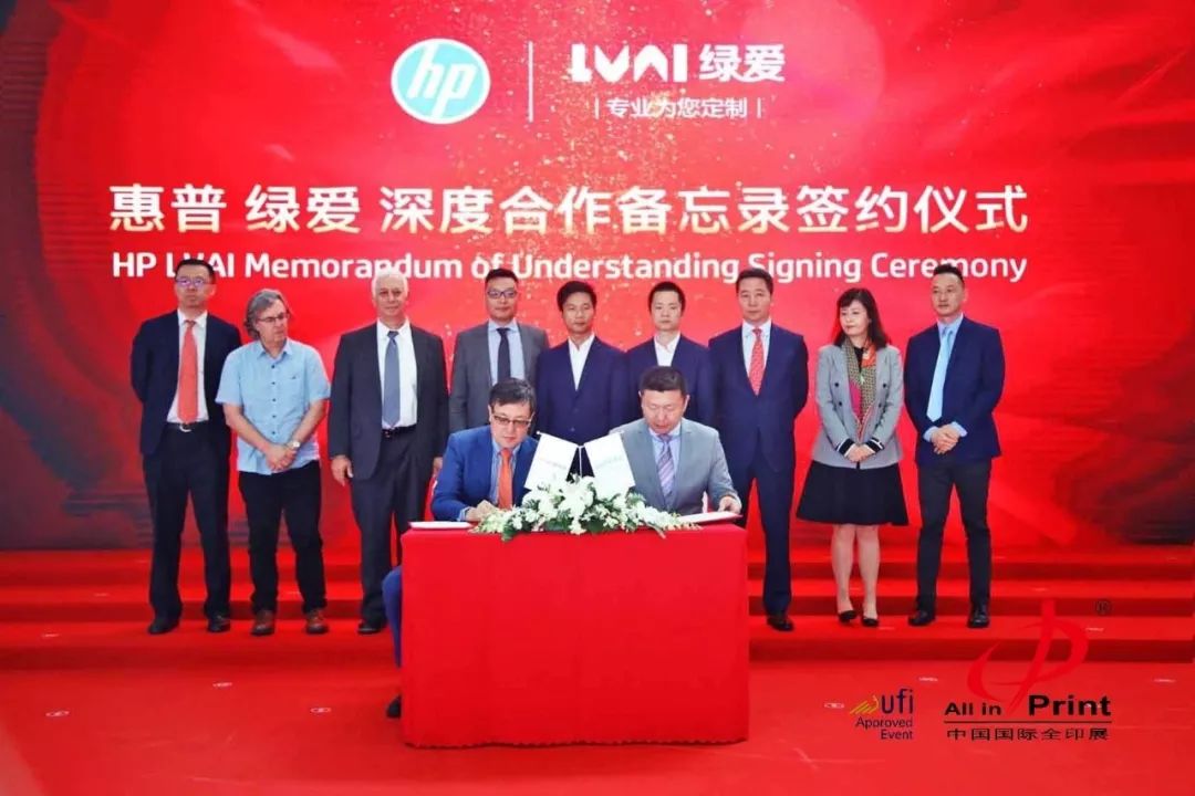 惠普绿爱合作备忘录签约典礼布景前的多人及桌面文件