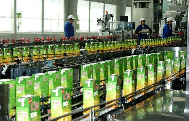 输送线上的绿色饮料纸盒及戴帽工作人员