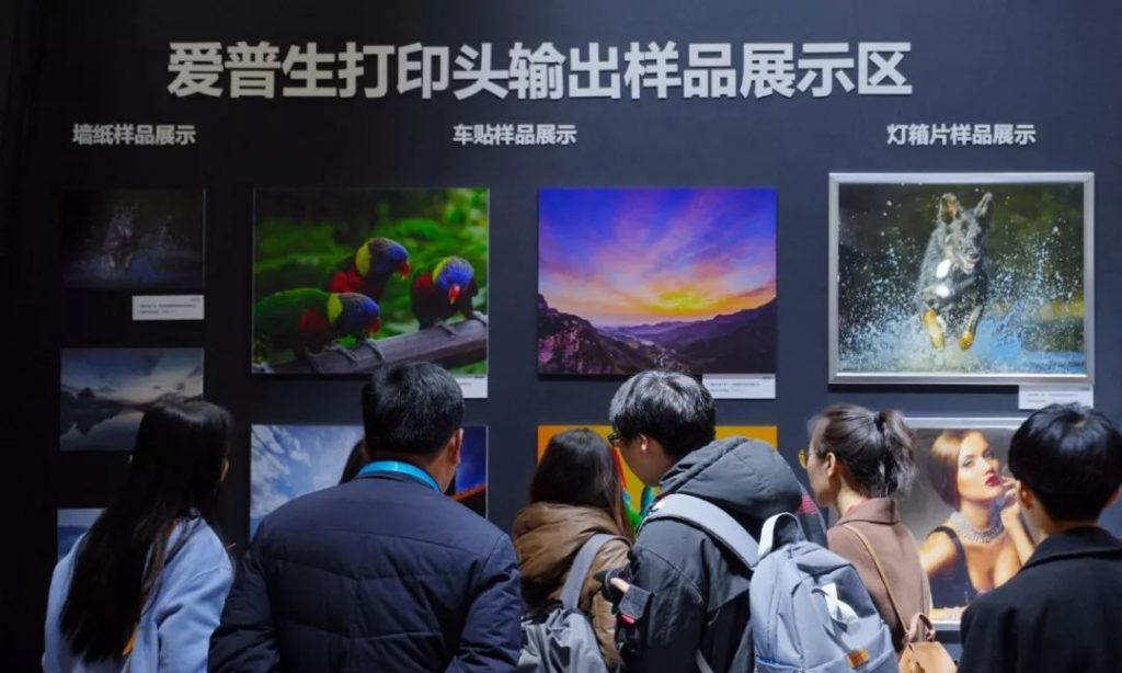 爱普生打印头输出样品展示墙前的人群