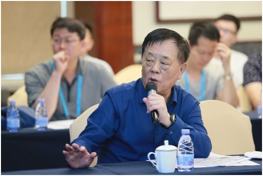 会议桌旁一名男子手持发话器讲话