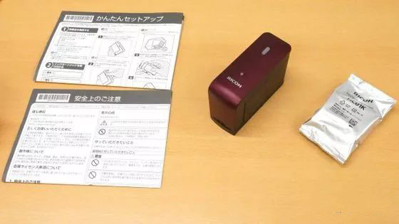 桌上的红色RICOH设备、注明纸和银色包装袋