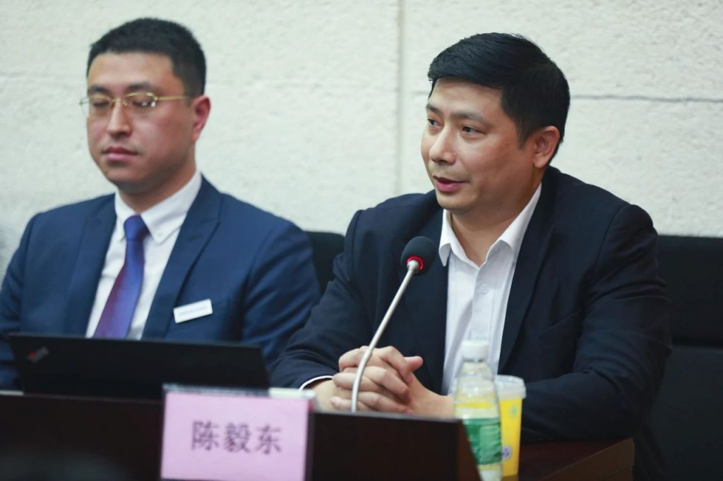 会议桌前两位男子、麦克风与陈毅东桌牌
